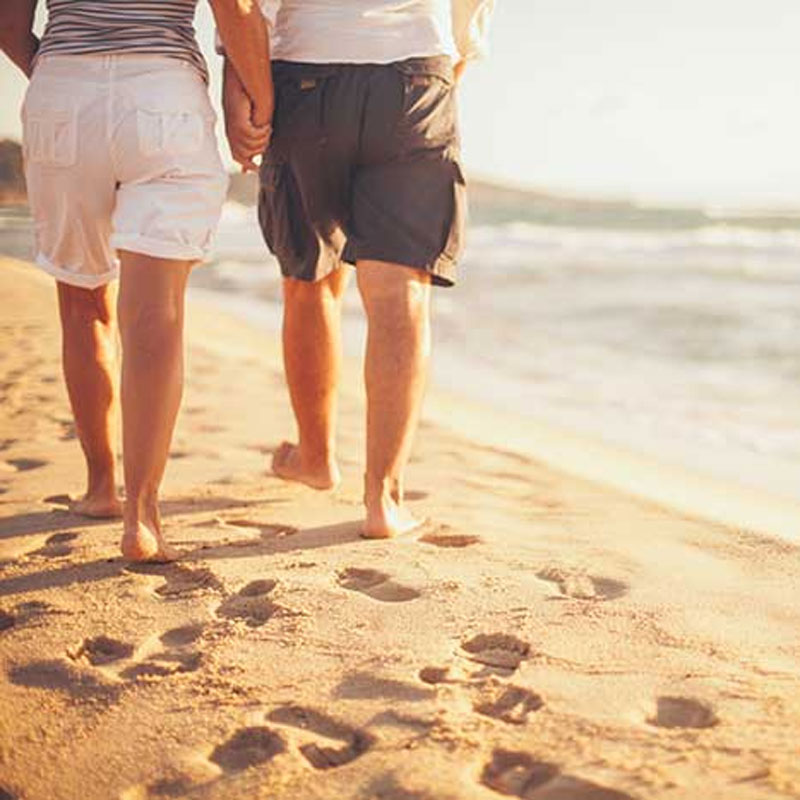 elderly couple walking on beach